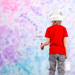 cute child boy back view red t shirt grey jeans painting colorful wall