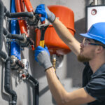 man installs heating system house checks pipes with wrench 1
